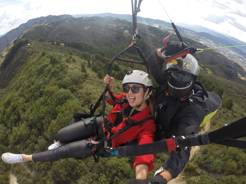 Mujer tomándose una selfie con su piloto mientras vuelan en parapente - VUELOS EN PARAPENTE